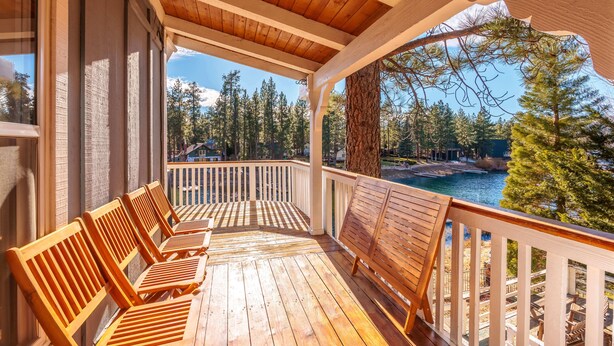 Una terrazza in legno con panche che si affaccia su un lago e una foresta.