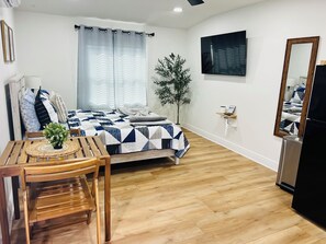 A bedroom with a bed, a bedside table with a plant, a mirror, and a wall-mounted TV. - A blue break for two. Directions to the Casino (Tampa)