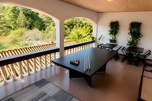 A dining area with a long table, chairs, and a view of greenery outside. - Pousada Casarão (Campo Alegre)