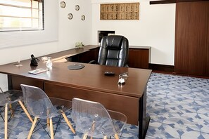 A conference room with a long table, several chairs, a black leather chair, and a decorative wall piece. - Pousada Casarão (Campo Alegre)