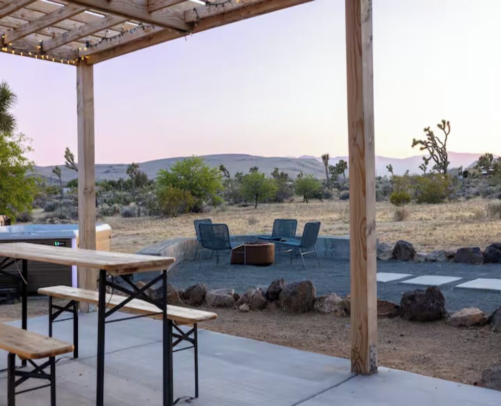 An outdoor patio with a wooden pergola, a table, and chairs.