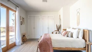 Ein Schlafzimmer mit einem Bett, einem Nachttisch, einem Kleiderschrank und einem Fenster mit Vorhängen.
