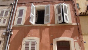 Un edificio con múltiples ventanas y una puerta, algunas con contraventanas.