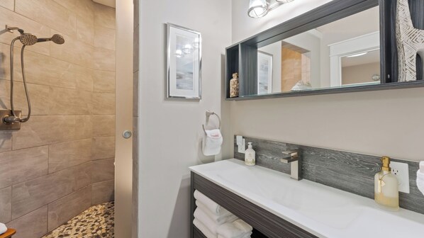 A bathroom with a shower, a large mirror, a sink with a towel rack, and a wall-mounted light fixture. - Lake Norman Lakefront w/ Private Beach, Dock, Hot Tub & Fire Pit Sandy Shore by Avantstay (Mooresville)