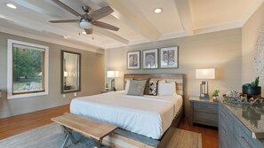 A bedroom with a bed, bedside tables, a desk, a ceiling fan, and framed artwork on the wall. - Lake Norman Lakefront w/ Private Beach, Dock, Hot Tub & Fire Pit Sandy Shore by Avantstay (Mooresville)