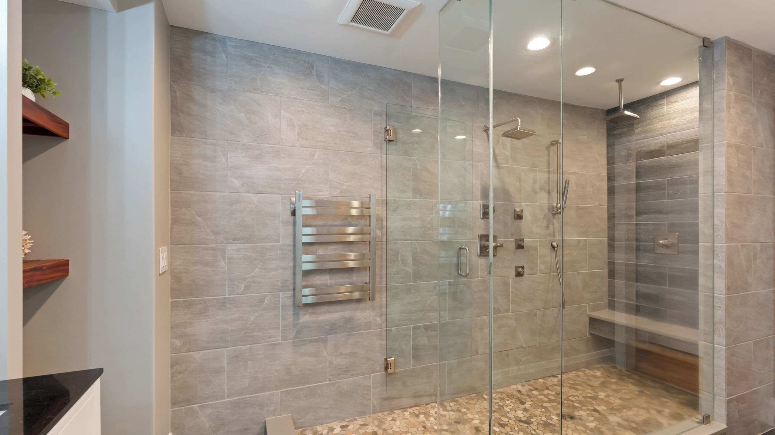 Un baño moderno con cabina de ducha de vidrio, perchero y tocador con encimera.