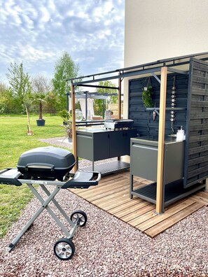 A patio area with a grill, seating, and a pergola structure.
