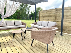 Un patio al aire libre con muebles de mimbre, una mesa redonda y un dosel blanco.