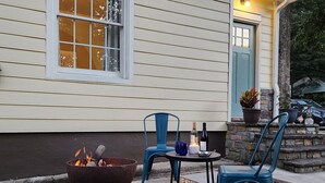 Een buitenruimte met zitgedeelte, een vuurkorf, twee stoelen en een tafel met drankjes en een kaars.