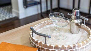 Een dienblad met twee glazen en een cocktailshaker op een houten ondergrond.