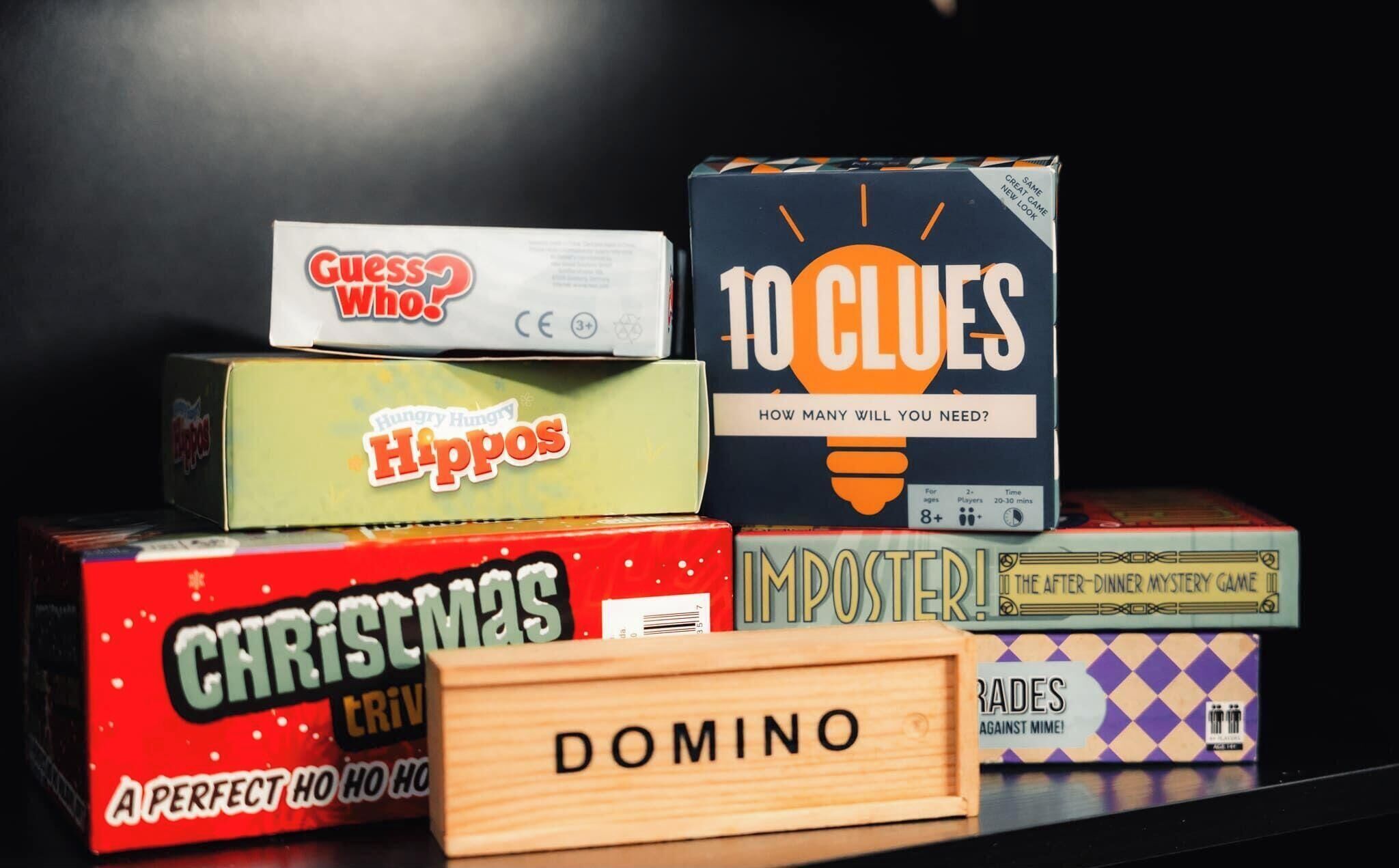 Une collection de jeux de société comprenant « Qui est-ce ? », « Dix indices », « Hippos », « Quiz de Noël », « Imposteur ! » et « Domino ».