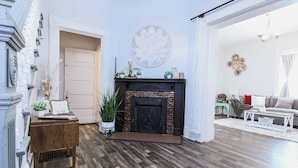 Un salon avec une cheminée, une porte et un mur décoré d’assiettes.