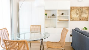 A modern kitchen with white cabinetry, a glass dining table, wicker chairs, and a grey sofa. - [Charm & Style Bari] Large Central Apartment (Bari)