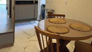 Una cocina moderna con armarios blancos, horno integrado y comedor con mesa redonda y sillas de madera.