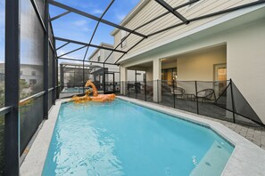 A swimming pool with a glass enclosure, surrounded by a covered patio area with outdoor furniture. - 7BD Luxury Villa w/ Pool, Ping-Pong & BBQ - Windsor Resort Access (Kissimmee)