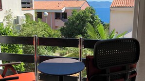 A balcony with a table and chairs, overlooking a coastal area with buildings and greenery. - Residence4a- Apartman Bianco - u blizini mora, idealan za opuštanje (Ravni)