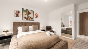 A modern bedroom with a large bed, a chair, a nightstand, and artwork on the wall. - Central Manchester Haven | City Views | Sleeps 4 (Manchester)