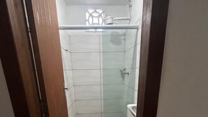 Une petite salle de bain étroite, comprenant des toilettes, un espace douche et un lavabo.