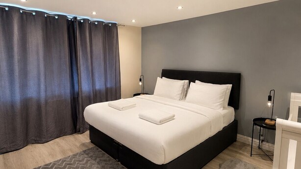 Une chambre à coucher moderne avec un grand lit, une table de chevet, une lampe et un berceau.
