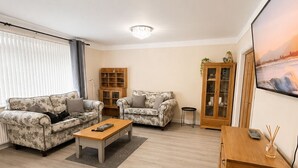 Un salon avec deux canapés, une table basse, un meuble et un tableau accroché au mur.