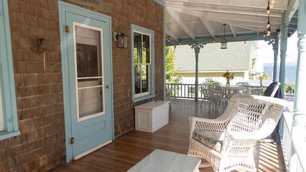A covered porch with wicker furniture, a brick wall, and a door labeled "Shearwater". - Perfect 4-bedroom house with AC in pleasant Historic Bayside. (Northport)