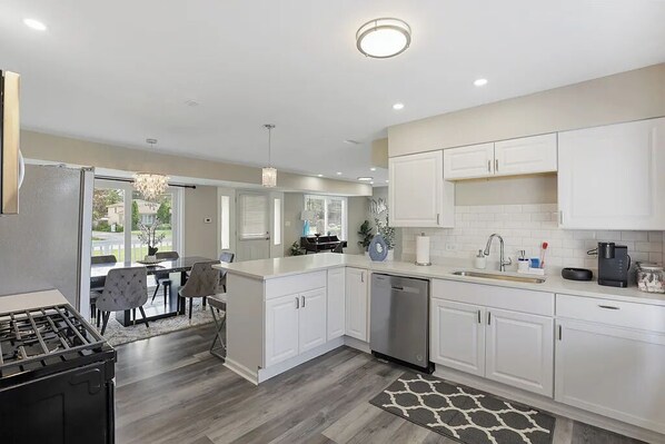 A modern kitchen with white cabinets, a stainless steel dishwasher, and a gas stove.