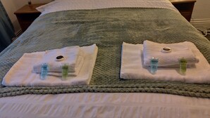 A neatly made bed with a green blanket, two towels with toiletries, and a bedside lamp. - Lovely 5 bedrooms in a quiet area where guests can enjoy their stay near thepark (Tyne and Wear)