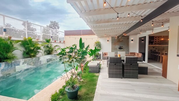 Patio moderno all'aperto con piscina, posti a sedere e luci decorative.