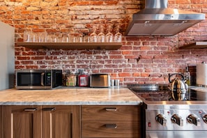 Une cuisine avec un mur en briques, des appareils électroménagers en acier inoxydable et un plan de travail en bois.