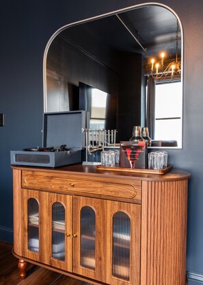 A wooden bar area with a mirrored cabinet, a jukebox, and a cocktail book on the counter. - Hollyhock Suite 401: 4 bed/2 bath with soaking tub (Louisville)