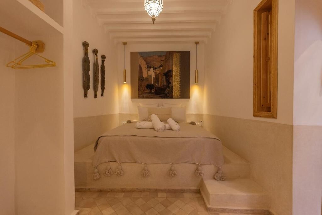 Un dormitorio con una cama, un cuadro en la pared y una lámpara colgante.