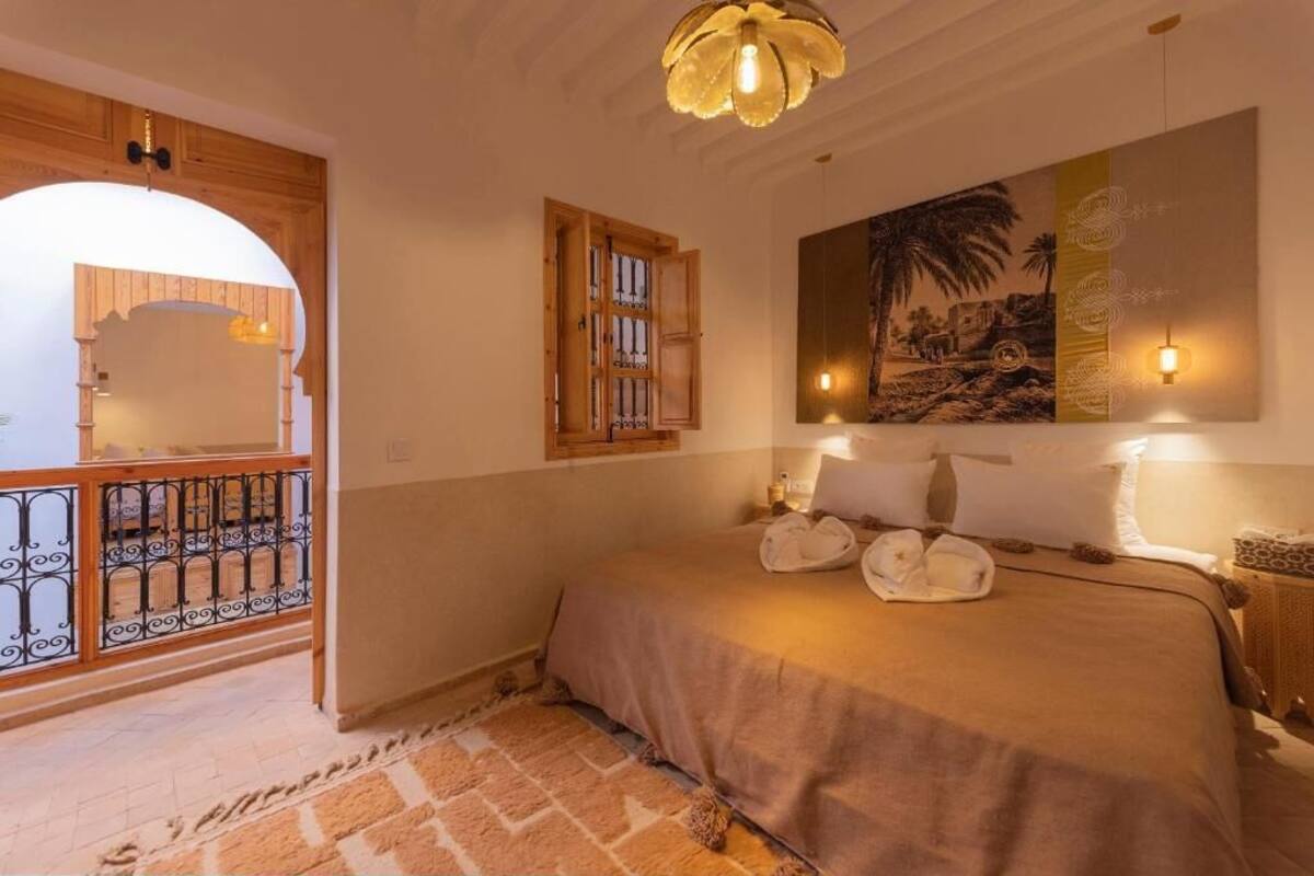 A bedroom with a bed, a wooden door, a window, and a painting on the wall.