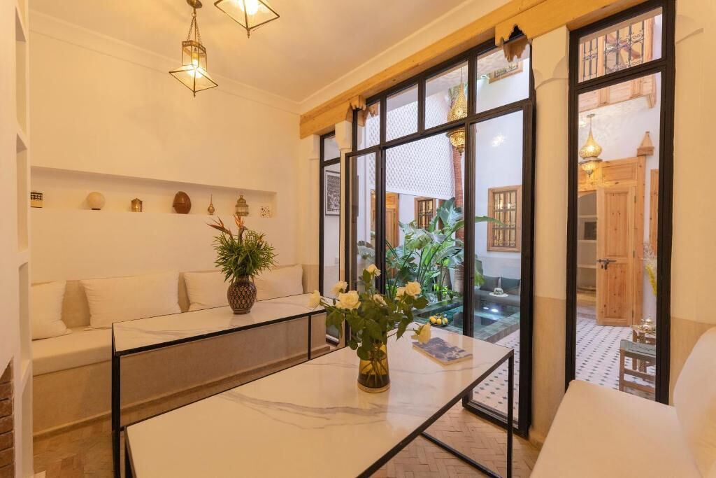 Een moderne woonkamer met een glazen salontafel, een bank en een potplant.