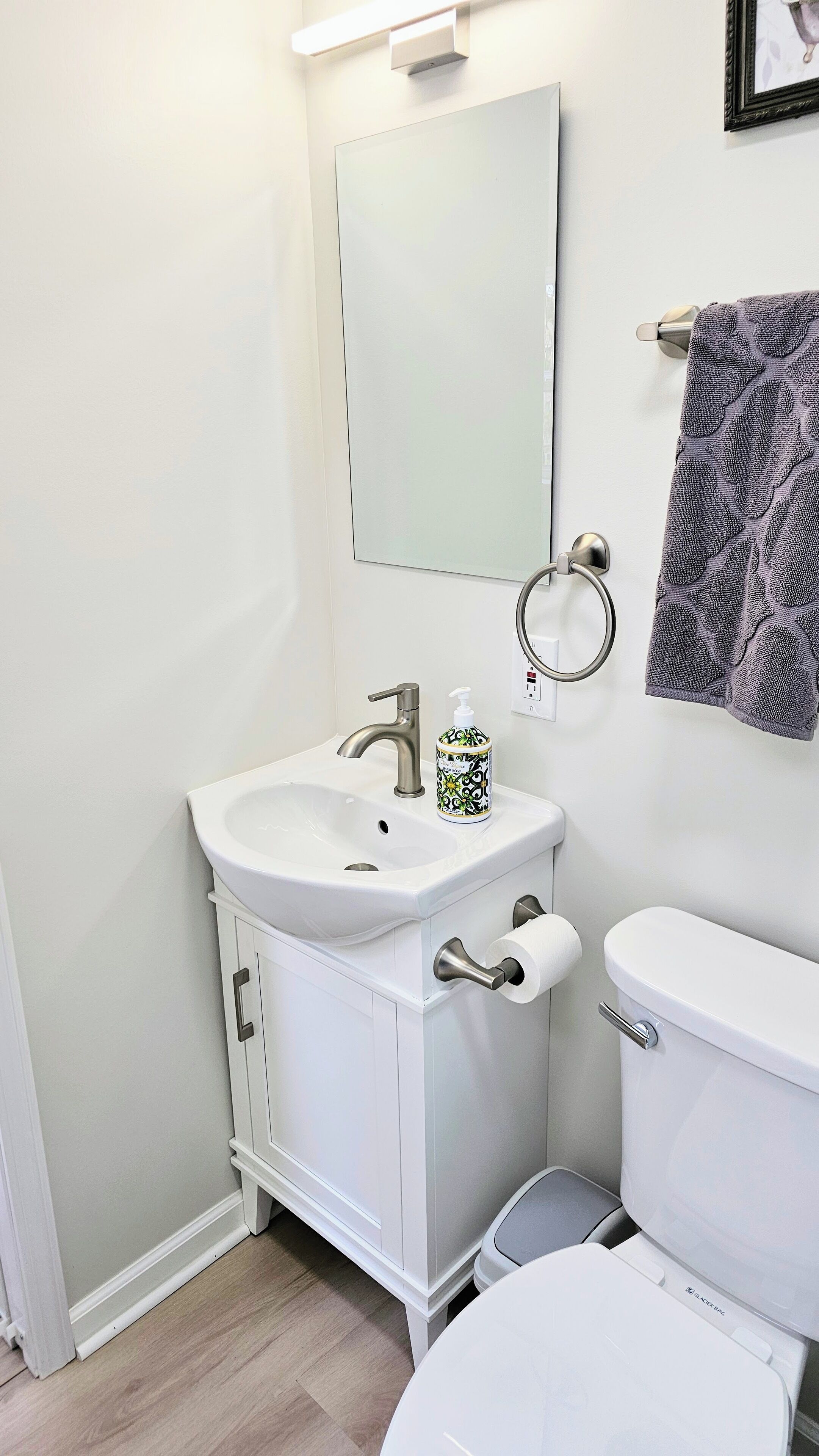 A bathroom with a white sink, a mirror, a toilet, and a towel rack.