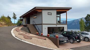 Une maison moderne à deux étages, dotée d’un garage, d’une allée décorative et offrant une vue sur les montagnes.