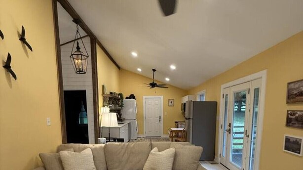 A living room with a sectional sofa, a ceiling fan, recessed lighting, and a view of the kitchen and dining area through glass doors. - The Cottage by Raven`s Keep (Jackson)