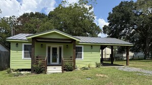 A small, single-story house with a green exterior and a metal roof. - The Cottage by Raven`s Keep (Jackson)
