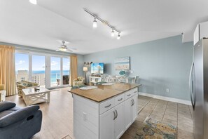 Una cocina moderna con una isla central, muebles blancos y vistas al exterior.