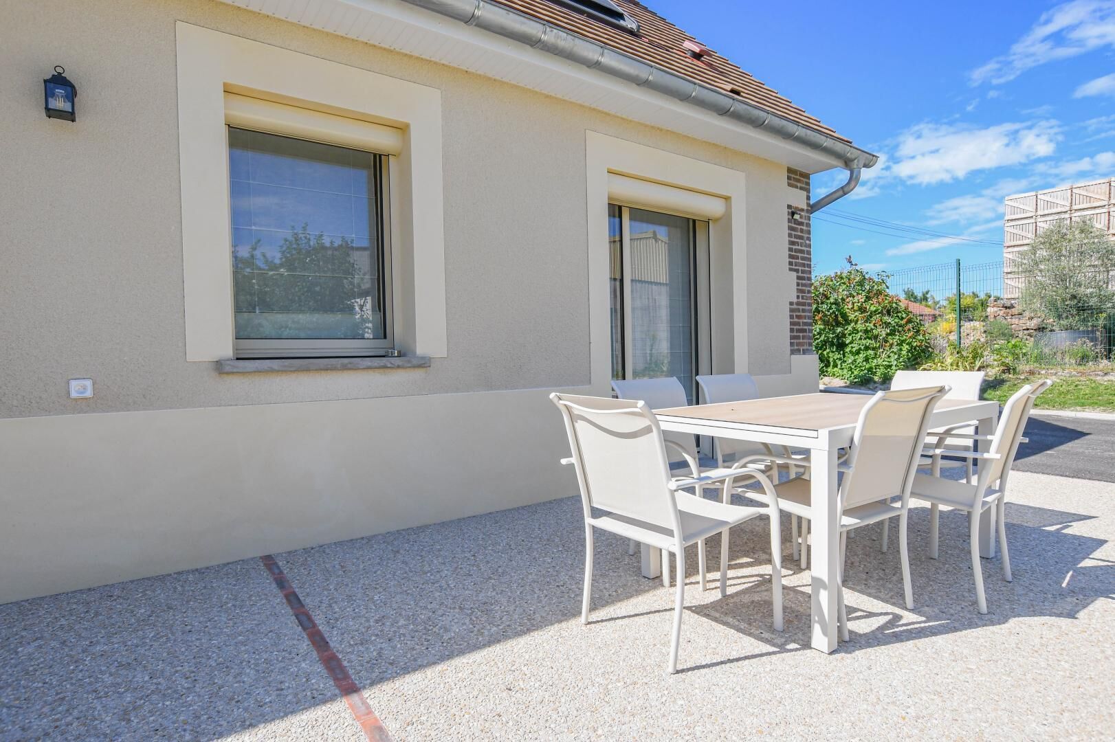 A building with a patio area featuring a table and chairs, a window, and a door.
