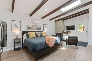 Un dormitorio con una cama grande, televisión, chimenea y techo de madera.