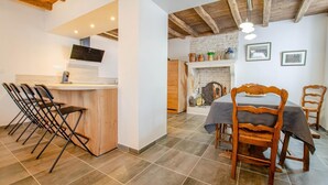Un comedor con mesa y sillas, una cocina con televisor y chimenea.