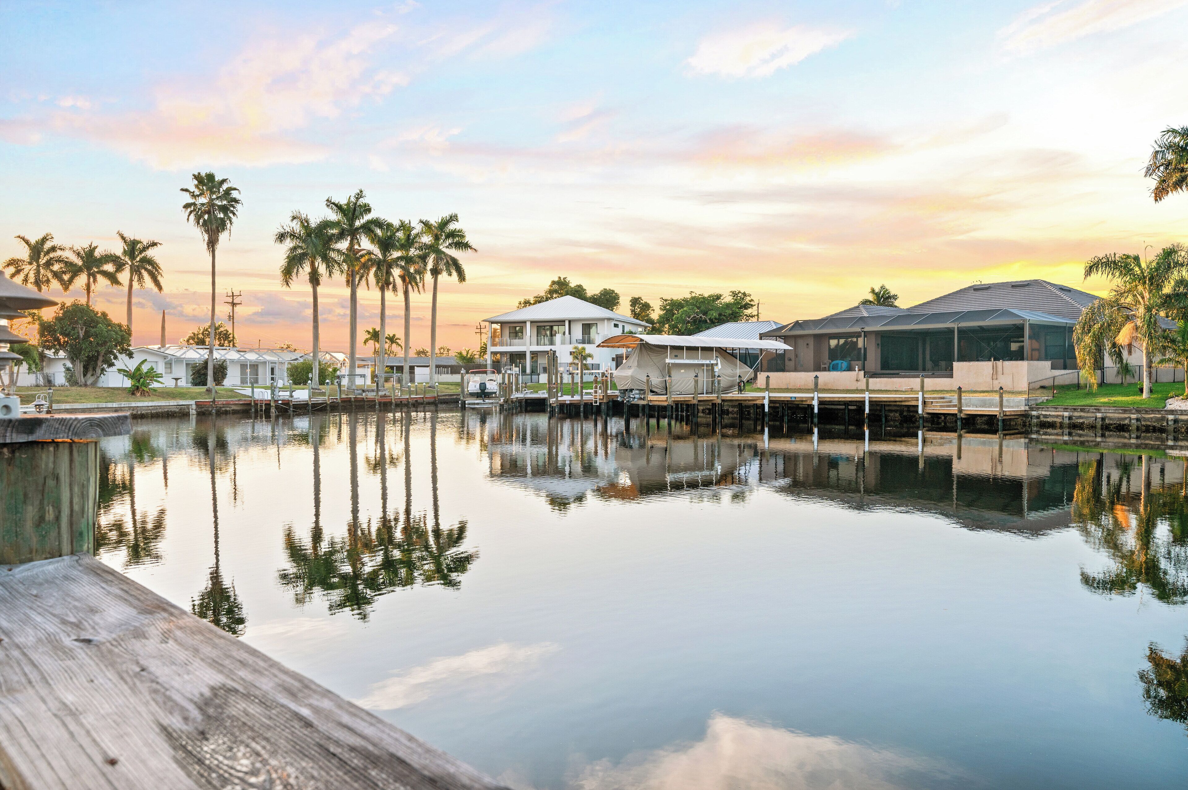 A waterfront property with multiple buildings, a dock, and palm trees.
