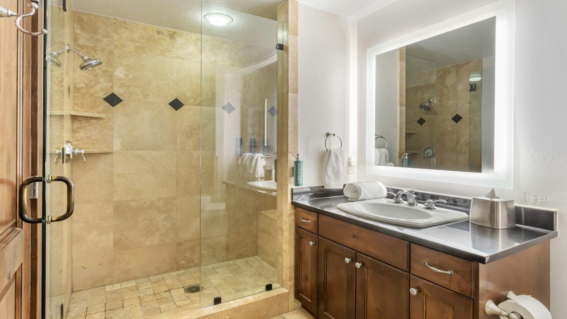 Une salle de bain moderne avec une douche à parois de verre, un grand miroir et des meubles en bois.