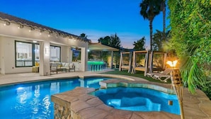 A swimming pool with a stone edge, a bar area, and a covered seating area. - Melrose Place: Pool, Spa, Fire Pit, Gameroom, EV! (Indio)