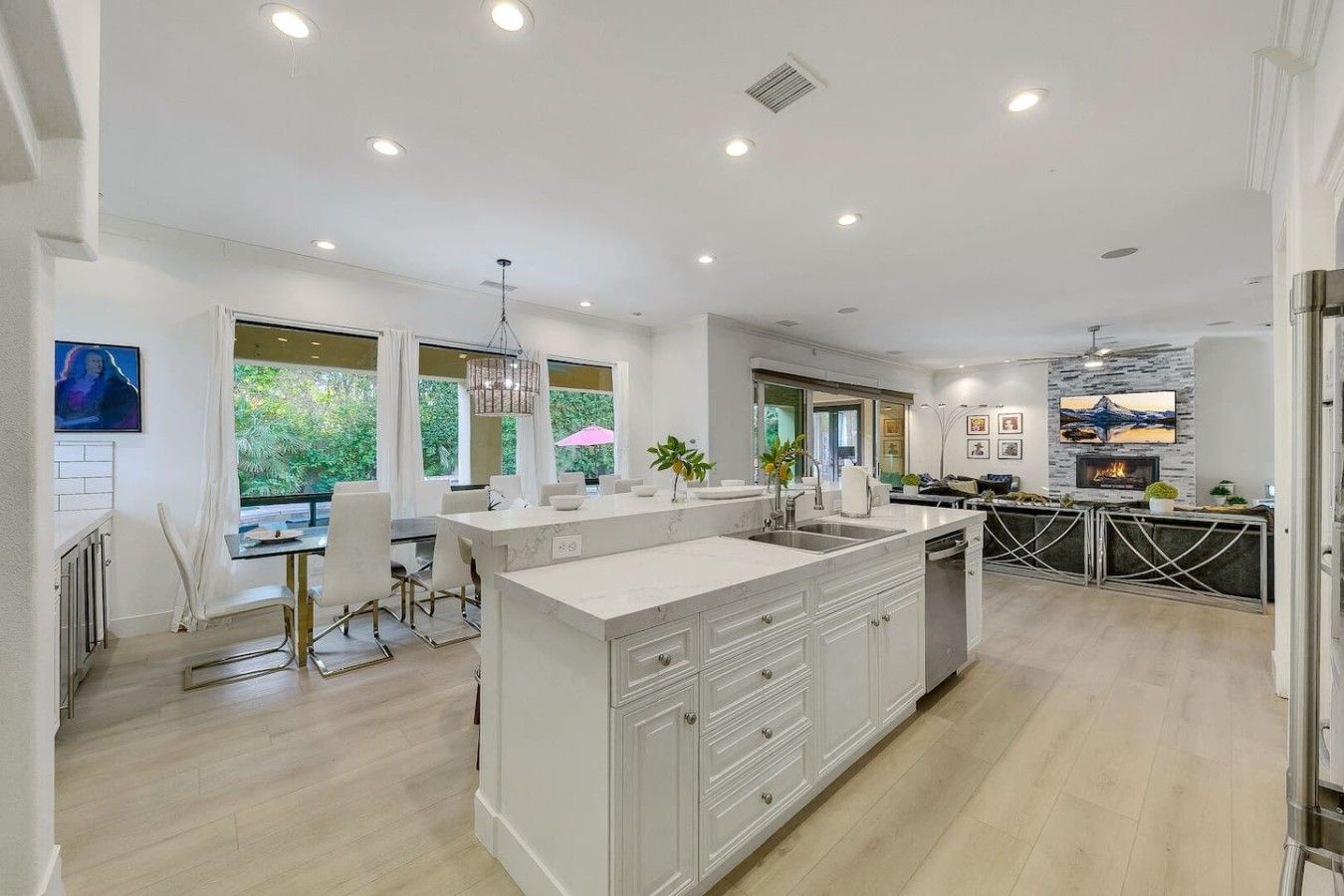 A modern kitchen with a large island, white cabinetry, and a dining area with a table and chairs.