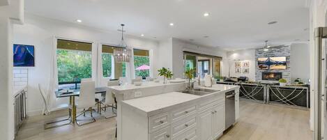 A modern kitchen with a large island, white cabinetry, and a dining area with a table and chairs.