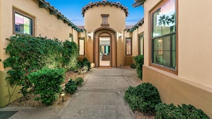 A building with a central entrance, a covered walkway, and surrounding greenery. - Melrose Place: Pool, Spa, Fire Pit, Gameroom, EV! (Indio)