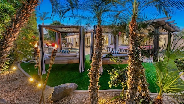 A garden with palm trees, a pergola, and a pool area. - Melrose Place: Pool, Spa, Fire Pit, Gameroom, EV! (Indio)