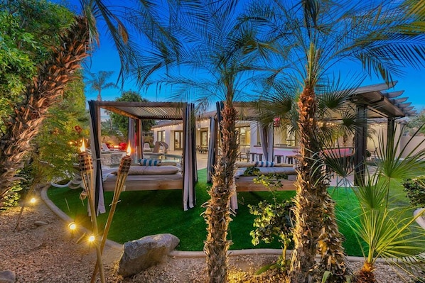 A garden with palm trees, a pergola, and a pool area. - Melrose Place: Pool, Spa, Fire Pit, Gameroom, EV! (Indio)