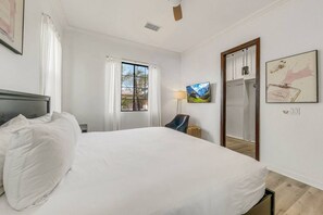 Ein Hotelzimmer mit einem großen Bett, einem Fernseher, einem Kleiderschrank und einem fenster mit Vorhängen.